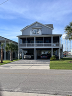 Two-story house with a carport and palm trees on a clear day. N. Myrtle Beach