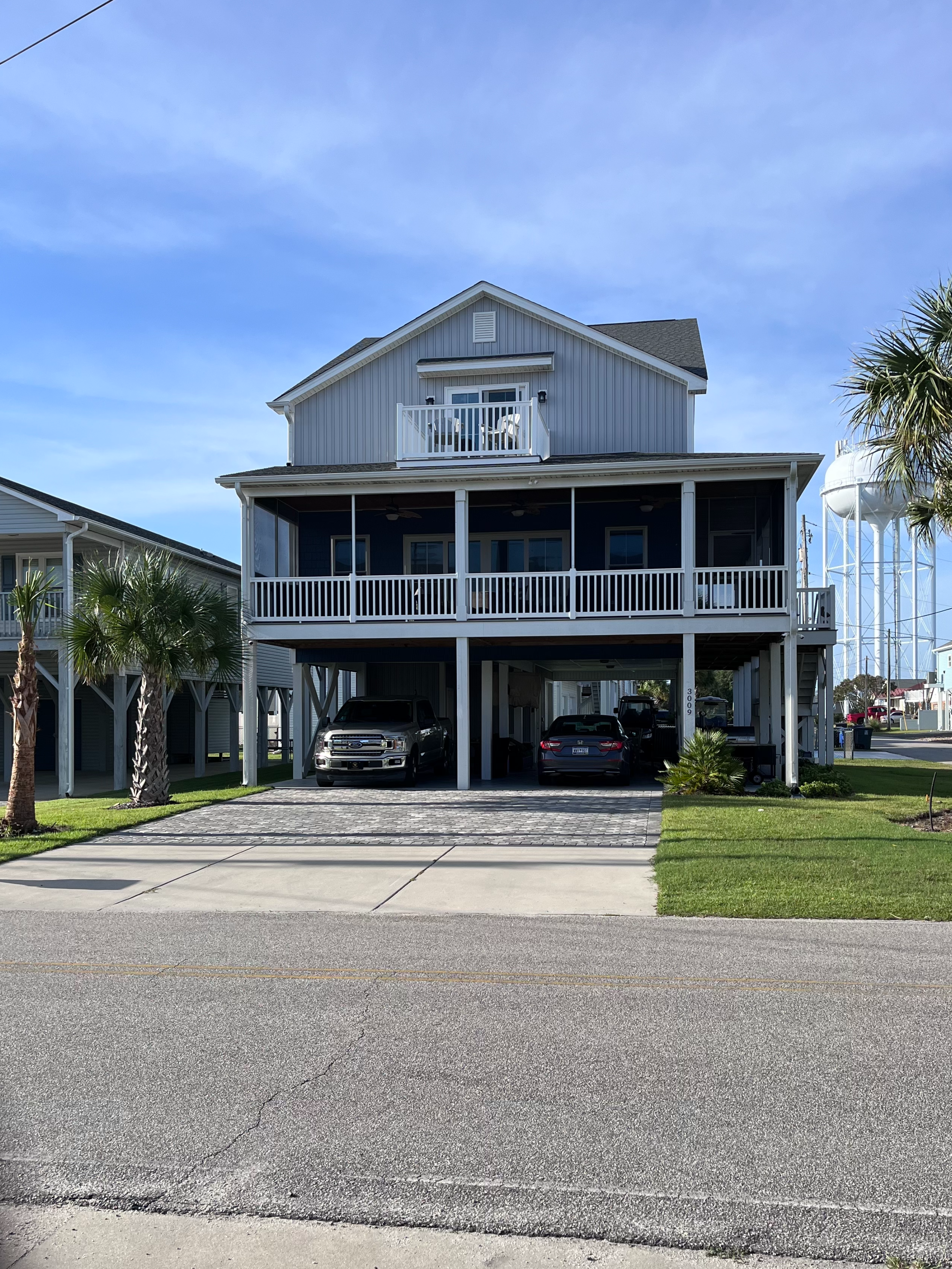 Two-story house with a carport and palm trees on a clear day. N. Myrtle Beach