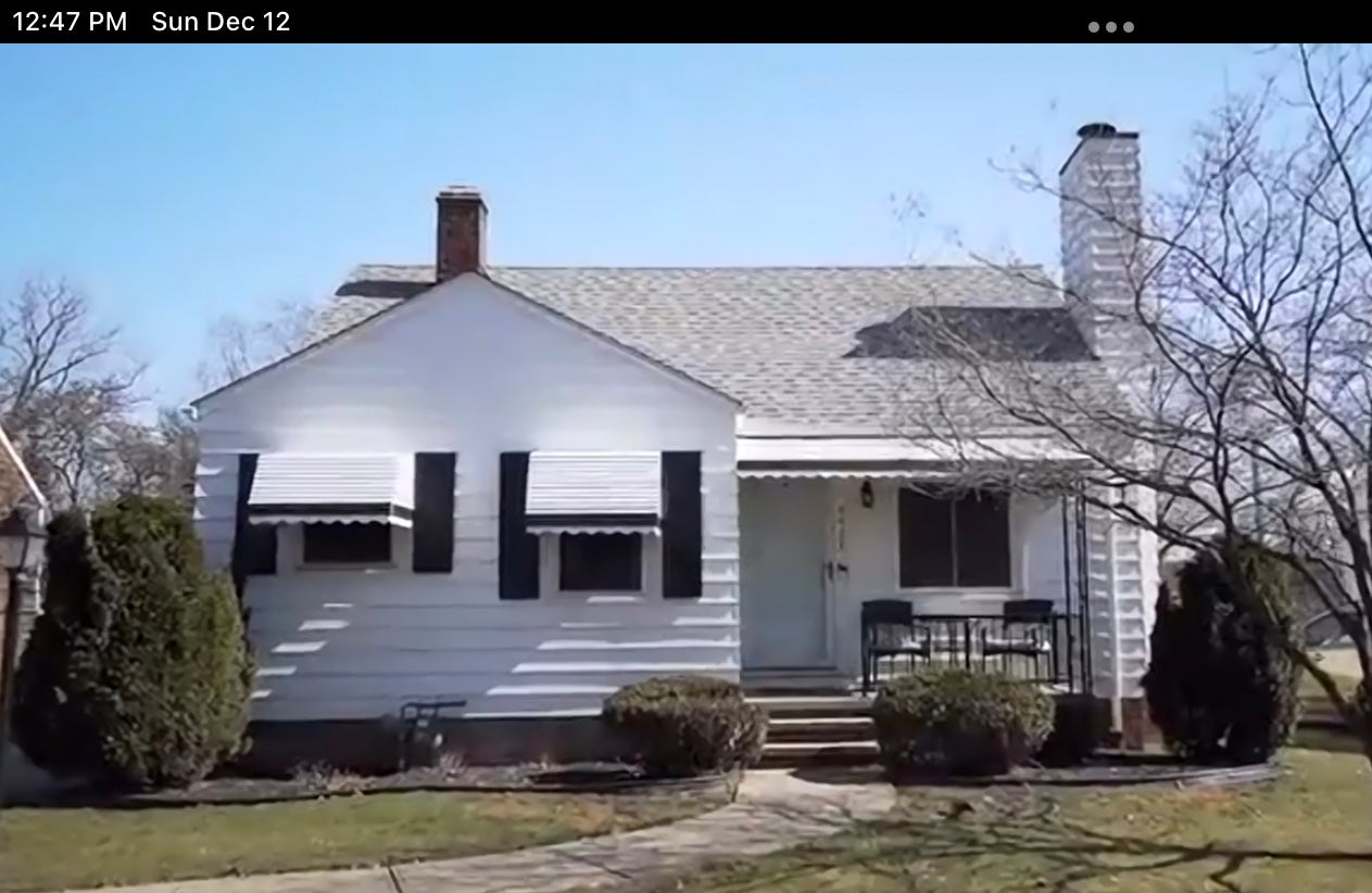 White house with black shutters on a clear day. 